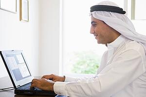 Man in office with laptop smiling (high key/selective focus)