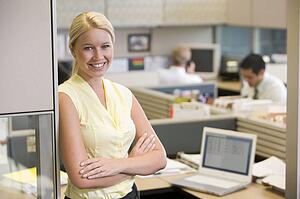 Businesswoman standing in cubicle smiling