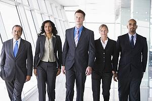 Group of co-workers walking in office space smiling (high key)