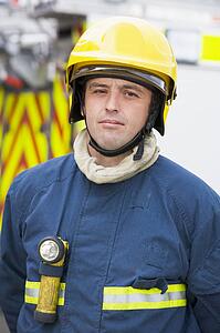 Fireman standing by fire engine wearing helmet