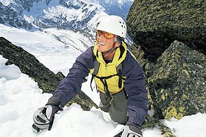 Mountain climber coming up snowy mountain smiling (selective focus)