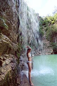 Woman outdoors standing by waterfall (high key)