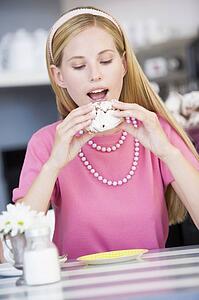 Young woman sitting at a table eating a sweet treat
