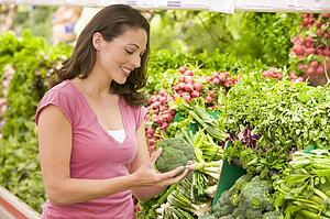 Woman shopping for broccoli at a grocery store