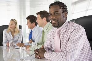 Four businesspeople in a boardroom smiling