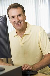 Man sitting at a computer terminal typing (high key)