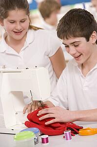 Male and female student using sewing machine