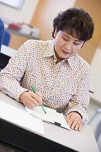Adult student in class taking notes
