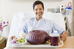 Woman Sitting In Hospital Bed With A Tray Of Food