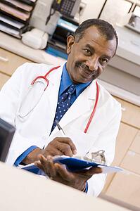 A Doctor Writing On A Clipboard At The Reception Area Of A Hospital