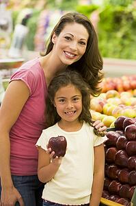 Woman and daughter shopping for apples at a grocery store