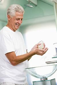 Man in bathroom applying aftershave and smiling