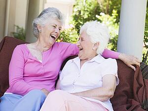 Two senior women sitting outdoors on a chair