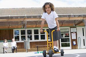 Student outside school on tricycle scooter