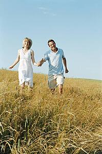 Couple walking outdoors holding hands smiling