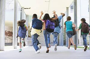 Six students running to front door of school excited