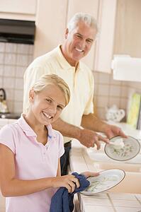 Grandfather And Granddaughter Cleaning Dishes Together