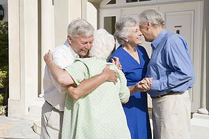 Two senior couples greeting each other with open arms
