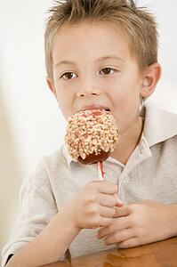 Young boy indoors eating candy apple