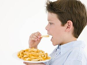 Young boy eating French fries
