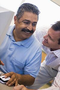 Two men at computer smiling and looking at each other (high key)