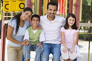 Family sitting on playground structure smiling (selective focus)