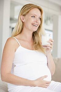 Pregnant woman with glass of milk smiling