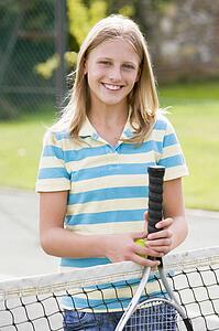 Young girl with racket on tennis court smiling