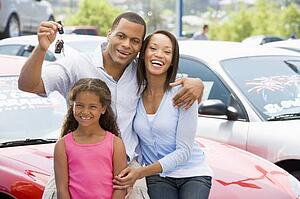 Mother and father with young daughter shopping for a new car