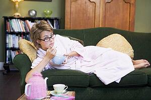 Young woman lying on sofa at home eating a sweet treat