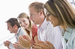 Four businesspeople applauding indoors smiling
