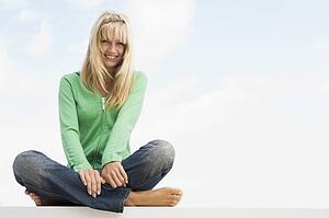 Blonde woman in a green sweater sitting outdoors