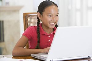 Young girl with laptop in dining room smiling