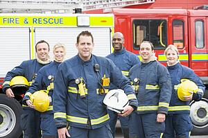 Six firefighters standing by fire engine