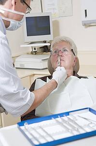 Dentist in exam room with woman in chair