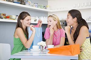 Three young woman sitting at a table taking a break from shopping