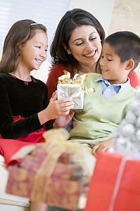 Mother Sitting With Her Son And Daughter, Exchanging Christmas Gifts