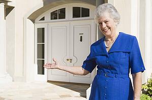 Senior woman standing outside her home