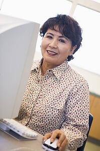 Woman at computer smiling and looking at monitor (high key)