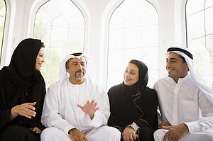Two couples sitting in living room talking and smiling (high key/selective focus)