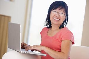Woman in living room with laptop smiling