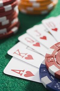 Playing cards making royal flush in hearts by poker chips (close up/selective focus)