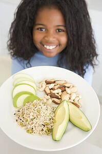 Young girl in kitchen eating rice fruit and nuts smiling