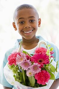 Young boy holding flowers smiling
