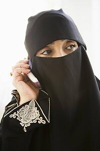 Woman indoors on cellular phone wearing veil (high key)