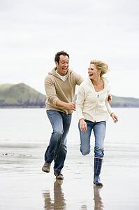Couple running on beach smiling