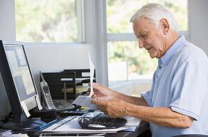 Man in home office with paperwork and computer