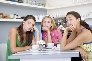 Three bored young women sitting at a table
