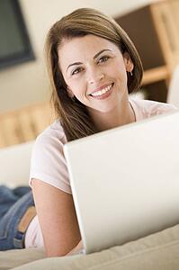 Woman in living room using laptop smiling