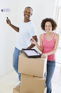 Couple with roller and paint in new home smiling
